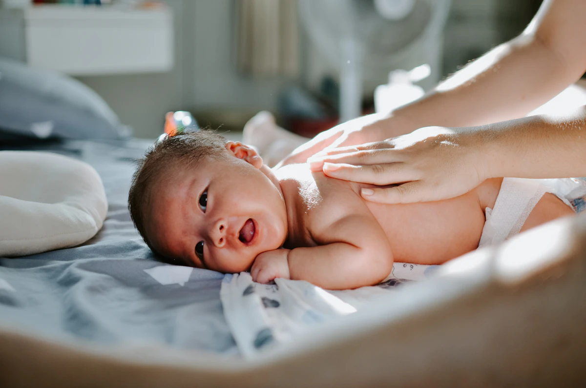 Une personne masse doucement le dos d’un bébé allongé